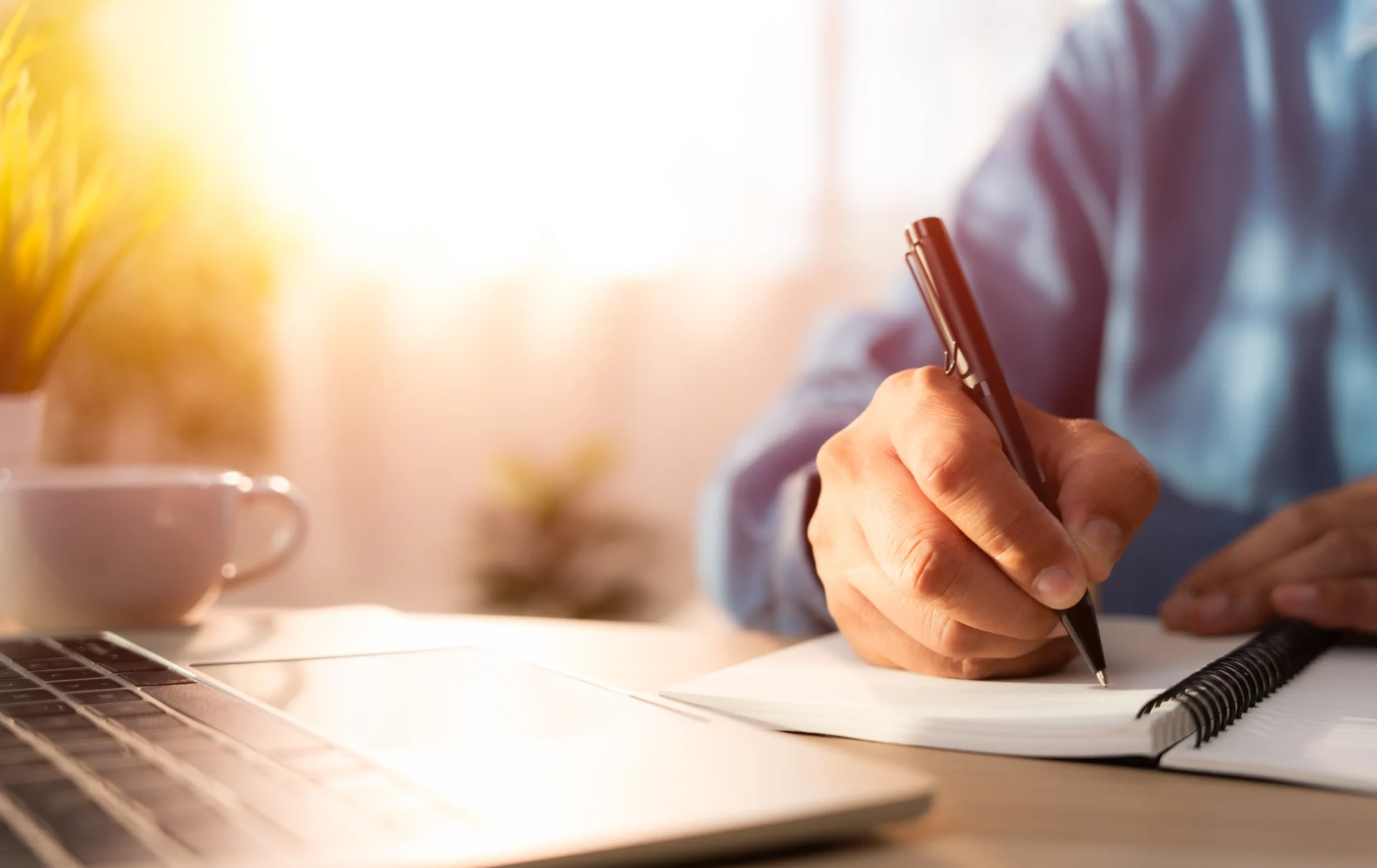 Person writing in a notebook with a pen.