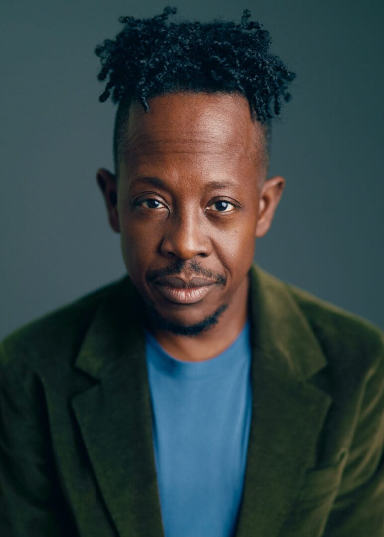 A man with dreadlocks and green jacket.