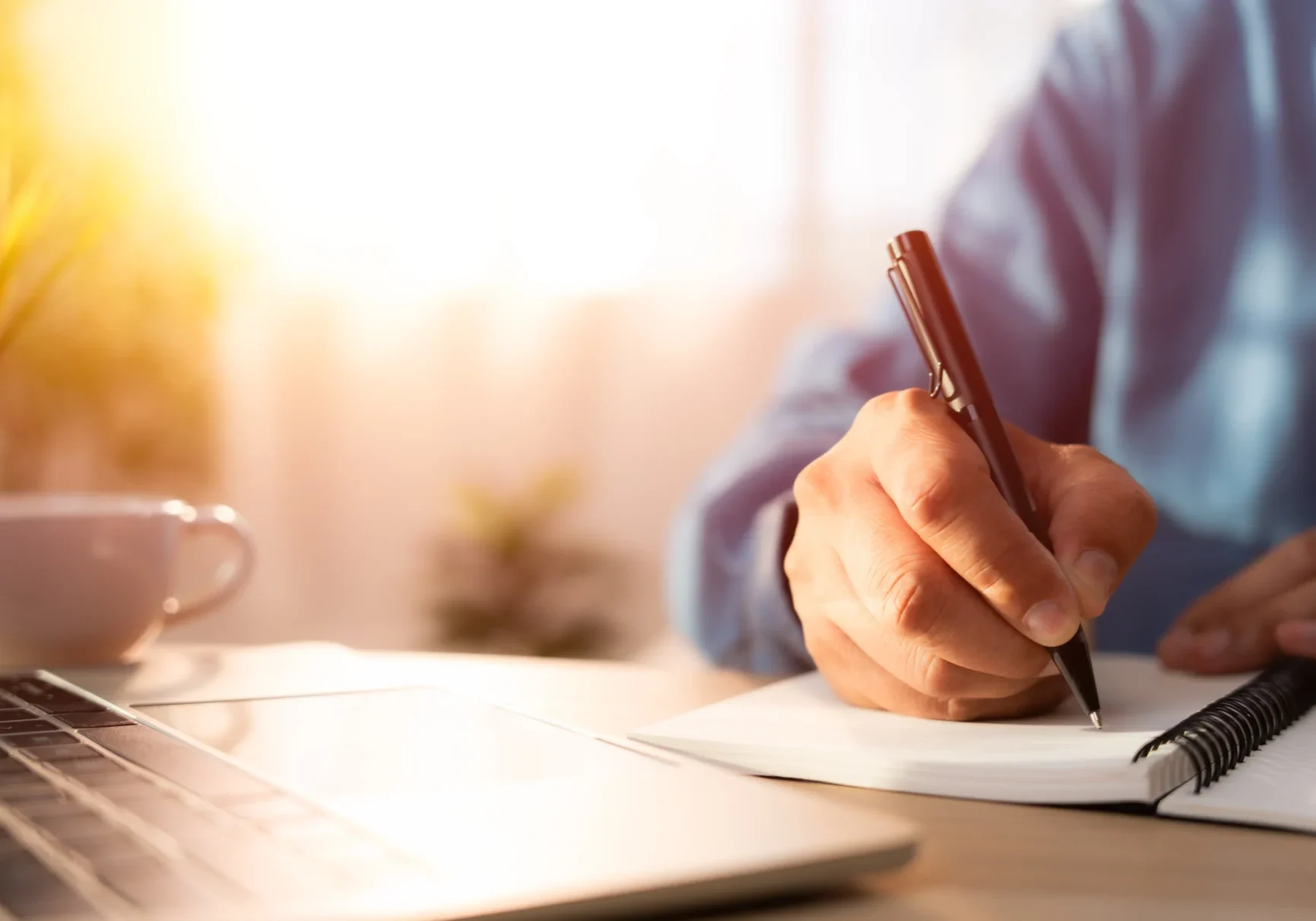 Person writing in a notebook with a pen.